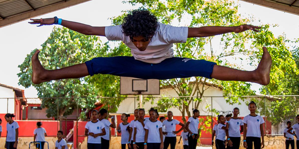 Garoto executa o salto esticando pernas e braços no ar.